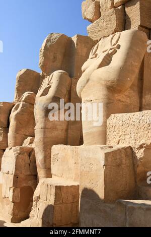 Fila di statue scolpite con cielo blu al Tempio di Karnak, Luxor, Egitto Foto Stock