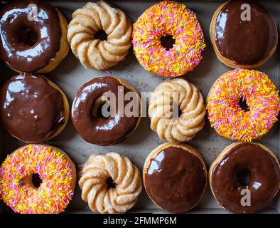 Sopra una dozzina di ciambelle assortite di caffè in una scatola. Foto Stock