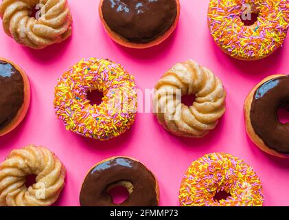 Testa di ciambelle assortite su uno sfondo rosa brillante. Foto Stock