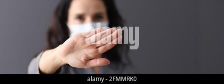 Donna in maschera medica protettiva tiene le mani in negativo gesto Foto Stock