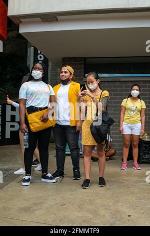 Medellin, Antioquia, Colombia - Marzo 27 2021: Giovane donna africana con un latino e una donna asiatica indossano abiti gialli, scattando foto e lo Foto Stock