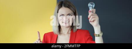 La donna d'affari sta tenendo la lampadina e girando capovolta Foto Stock