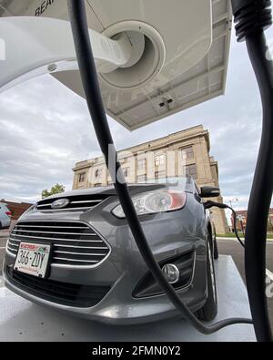 Racine, Wisconsin, Stati Uniti. 10 maggio 2021. Un'auto ibrida plug-in Ford C-Max Energi è collegata alla nuova stazione di ricarica per veicoli elettrici alimentata a energia solare installata dietro il municipio di Racine, Wisconsin la scorsa settimana, lunedì sera 10 maggio 2021. Le stazioni alimentate a energia solare come questa hanno una batteria di riserva, quindi non sono legate alla rete elettrica. La città ordinerà il suo primo veicolo elettrico per il reparto lavori pubblici e prevede l'acquisto di un maggior numero di veicoli elettrici e stazioni di ricarica in tutte le proprietà della città. (Immagine di credito: © Mark HertzbergZUMA Wire) Foto Stock