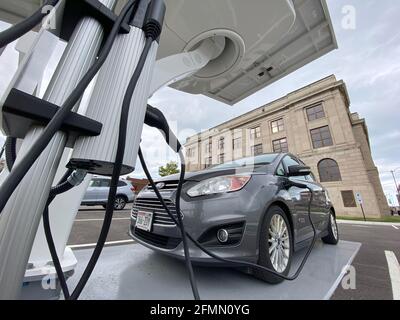 Racine, Wisconsin, Stati Uniti. 10 maggio 2021. Un'auto ibrida plug-in Ford C-Max Energi è collegata alla nuova stazione di ricarica per veicoli elettrici alimentata a energia solare installata dietro il municipio di Racine, Wisconsin la scorsa settimana, lunedì sera 10 maggio 2021. Le stazioni alimentate a energia solare come questa hanno una batteria di riserva, quindi non sono legate alla rete elettrica. La città ordinerà il suo primo veicolo elettrico per il reparto lavori pubblici e prevede l'acquisto di un maggior numero di veicoli elettrici e stazioni di ricarica in tutte le proprietà della città. (Immagine di credito: © Mark HertzbergZUMA Wire) Foto Stock