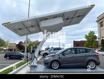 Racine, Wisconsin, Stati Uniti. 10 maggio 2021. Un'auto ibrida plug-in Ford C-Max Energi è collegata alla nuova stazione di ricarica per veicoli elettrici alimentata a energia solare installata dietro il municipio di Racine, Wisconsin la scorsa settimana, lunedì sera 10 maggio 2021. Le stazioni alimentate a energia solare come questa hanno una batteria di riserva, quindi non sono legate alla rete elettrica. La città ordinerà il suo primo veicolo elettrico per il reparto lavori pubblici e prevede l'acquisto di un maggior numero di veicoli elettrici e stazioni di ricarica in tutte le proprietà della città. (Immagine di credito: © Mark HertzbergZUMA Wire) Foto Stock