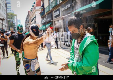 Messico, Messico. 10 maggio 2021. Un peddler è stato sanitizzato da un Luchador messicano. 'La Brigata due delle tre cascate' chiamato dal messicano City Youth Institute ha fatto un giro di Madero Street nel centro storico incoraggiando l'uso di maschere facciali, poiché la pandemia continua ancora nonostante il semaforo epidemiologico giallo. (Foto di Guillermo Diaz/SOPA Images/Sipa USA) Credit: Sipa USA/Alamy Live News Foto Stock