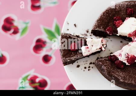 Torta al cioccolato senza flourless con panna e frutti di bosco su un rosa sfondo Foto Stock