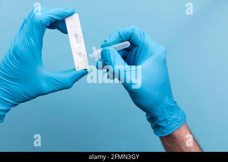 Medico in guanti blu utilizzando un flusso laterale covid-19 test kit Foto Stock