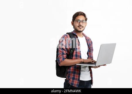 Studente universitario indiano che usa un computer portatile su sfondo bianco. Foto Stock