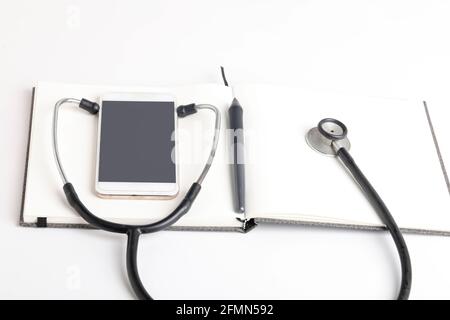 Stetoscopio nero che giace sul diario, medicina. Foto Stock