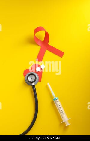 Posto di lavoro del medico con stetoscopio, compresse in blister, siringa su sfondo giallo. Foto Stock