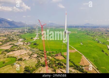 Turbina eolica in riparazione, assistita da gru e ascensore. Centrale eolica. Prato verde con turbine eoliche che generano elettricità Foto Stock