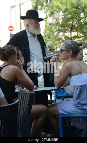 Un ebreo ortodosso israeliano si avvicina alle donne laiche israeliane in un caffè all'aperto a Tel-Aviv, Israele. Foto Stock