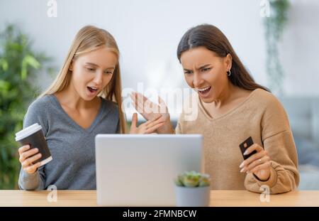 Due giovani donne che fanno acquisti online. Ragazze che fanno shopping a casa. Foto Stock