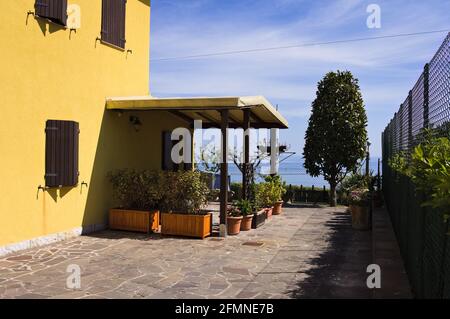 Un patio con gazebo in legno circondato da piante e fiori (Fiorenzuola di Focara, Marche, Italia) Foto Stock