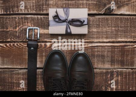 Confezione regalo per il giorno del padre con cintura accessori uomo e scarpe in pelle su sfondo in legno. Spazio di copia. Disposizione piatta. Foto Stock