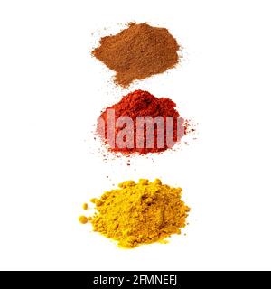 tre pile di spezie in polvere di vari colori su sfondo bianco Foto Stock