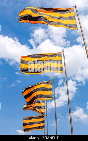 Bandiere di San Giorgio che sventolano nel vento sullo sfondo del cielo. Bandiere a strisce arancioni nere Foto Stock