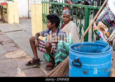 Mysuru, Karnataka, India - Gennaio 2018: Anziana operatrice indiana di servizi igienici seduta con un ragazzo sulle strade della città di Mysore. Foto Stock