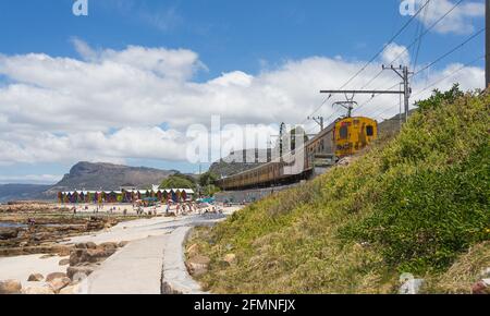 Linea ferroviaria e ferroviaria sudafricana sulla costa passando per la spiaggia di St James nel Capo Occidentale, Sud Africa Foto Stock