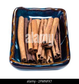 vista finale delle quills di cannella cassia in ciotola di ceramica ritaglio su sfondo bianco Foto Stock