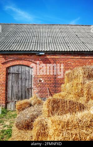 L'haystack d'oro di fronte ad un vecchio edificio di fienile in mattoni. Foto Stock