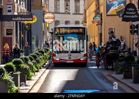 Autobus pubblico e carrozza trainata da cavalli su una strada stretta nella parte storica di Vienna, Austria. Foto Stock