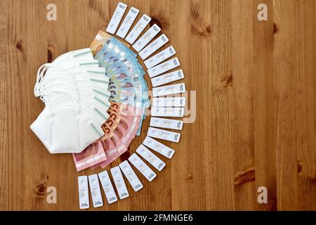 assicurazione sanitaria che copre i costi di corona maschere protettive viso e antigene rapido casa auto test banconote euro immagine verticale legno, moody, ue Foto Stock