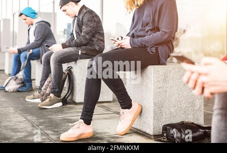 Gruppo di amici seduti e che utilizzano lo smartphone all'università Backyard break - Guy e ragazze addicted da mobile smart telefono Foto Stock