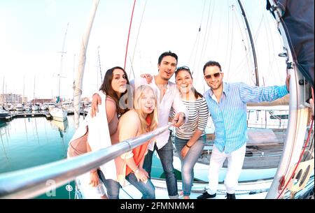 Gruppo di amici che prende foto selfie con bastone su vela di lusso Festa in barca - concetto di amicizia con giovani milleniali divertirsi insieme Foto Stock