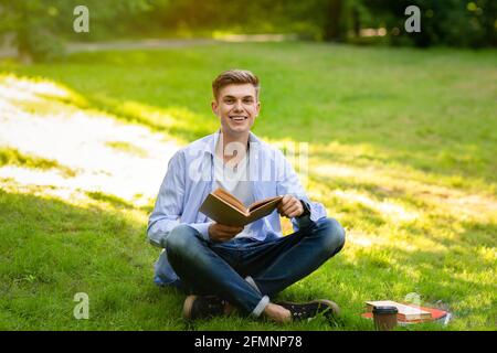 Studente adolescente ragazzo lettura libro all'aperto, imparare al campus universitario cortile Foto Stock