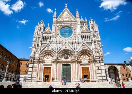 SIENA, ITALIA - 24 agosto 2020: La facciata della Cattedrale di Siena al sole e la finestra circolare attraverso la quale si può vedere il cielo con i turisti Foto Stock