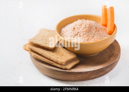 Salmone affumicato e formaggio morbido spalmato il pate con pane marrone e carote su sfondo bianco. Foto Stock