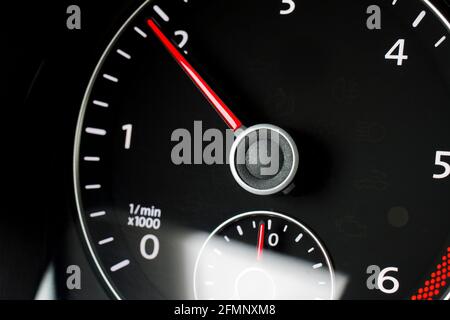 Primo piano di un contagiri nero in un'auto - messa a fuoco sull'ago rosso Foto Stock