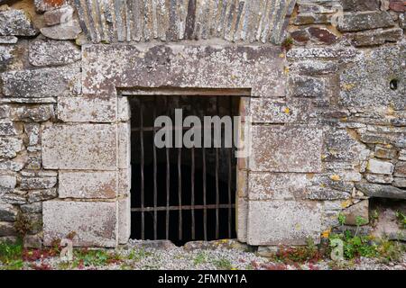 Barred ingresso a una prigione nella parete medievale di un vecchio castello rovina Foto Stock