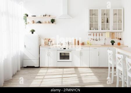 Cucina con pareti chiare, mobili bianchi e piccolo frigorifero in sala da pranzo design scandinavo Foto Stock
