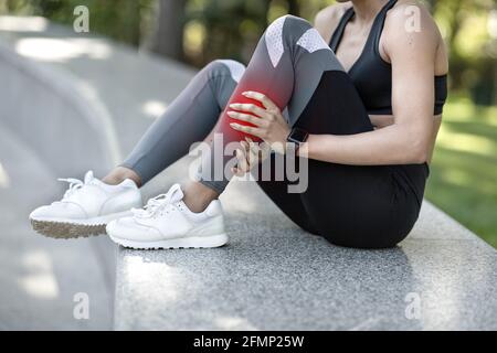Donna irriconoscibile in sportswear sfregando la gamba Foto Stock