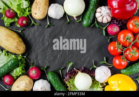 Verdure fresche e piantine di girasole su sfondo di pietra nera con posto per il testo. Sfondo vegetale. Foto Stock