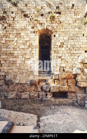 Antico fortilizio di Rodi intemperie in mattoni e muro di pietra con vuoto Porta ad arco sotto la luce del sole in estate Grecia Foto Stock