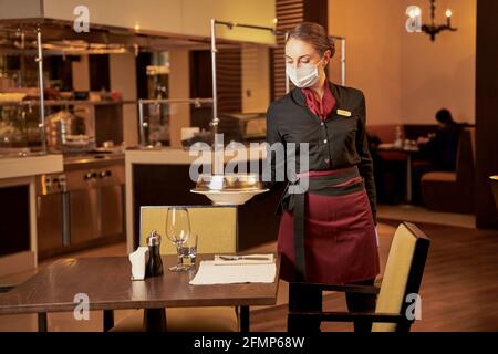 Cameriera che mette un pasto al ristorante su un tavolo preparato Foto Stock
