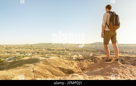Indietro vista giovane turista con zaino in piedi sul bordo della valle nella regione della Cappadocia, Turchia Foto Stock