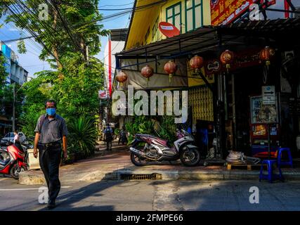 Un uomo che indossa una maschera attraversa la strada a Talat noi, Bangkok, Thailandia Foto Stock