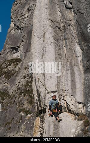 L'arrampicatore stanco si trova al centro della parete di arrampicata. Foto Stock