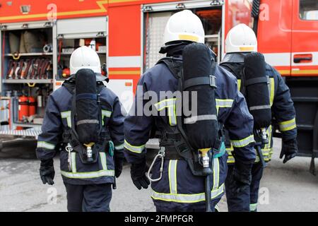 Ritratto di pompiere in uniforme davanti alla macchina antincendio e al team dei vigili del fuoco. Foto Stock