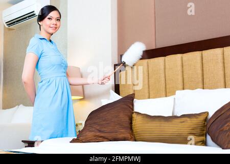 Cameriera spolvero in Asian hotel room Foto Stock