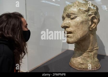 Londra, Regno Unito. 11 maggio 2021. Un membro dello staff posa con 'Pierre de Wissant, colossale Head', 1908, di Auguste Rodin. Anteprima a Tate Modern di "la realizzazione di Rodin", una nuova grande mostra di oltre 200 opere scultoree di Auguste Rodin, molte delle quali non sono mai state mostrate fuori dalla Francia. La mostra segna la riapertura del museo, in quanto il governo britannico facilita alcune restrizioni di blocco del coronavirus ed è aperta dal 18 maggio al 21 novembre. Credit: Stephen Chung / Alamy Live News Foto Stock