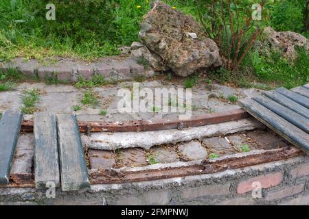 Vecchio panca fatto di mattoni con parti di legno perse a. parcheggio Foto Stock