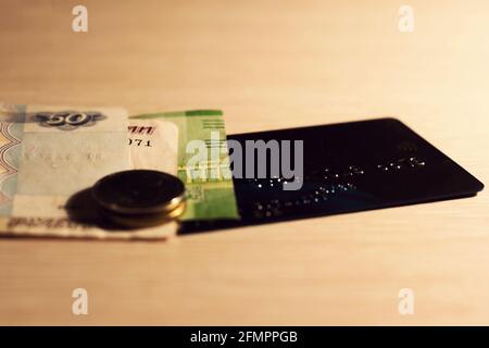 Carta bancaria e contanti senza contatto di plastica che giacciono sul tavolo. Foto Stock