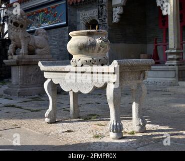 Bruciatore rotondo dell'incenso della pietra su un supporto curvo delle gambe davanti a Yuk Hui Kung, aka Tempio di Pak Tai, Cheung Chau, Hong Kong. Foto Stock