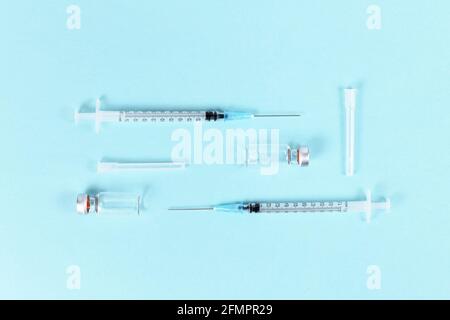 Flaconcini di vaccino con siringhe su sfondo blu Foto Stock